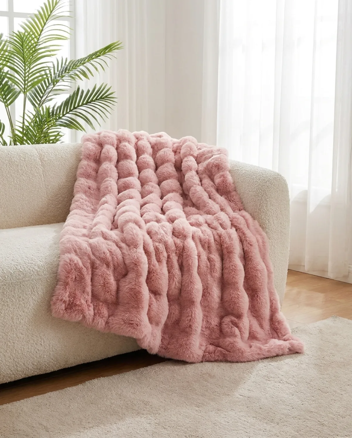 The Cloud Blanket in Blush draped over a couch